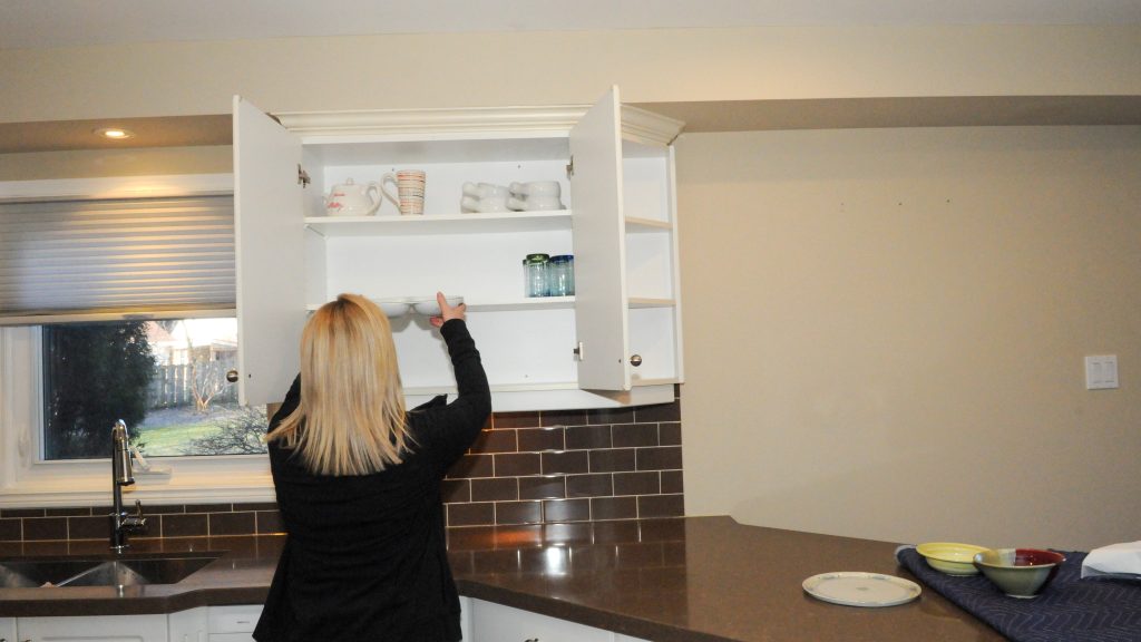Woman taking dish out of a cuboard