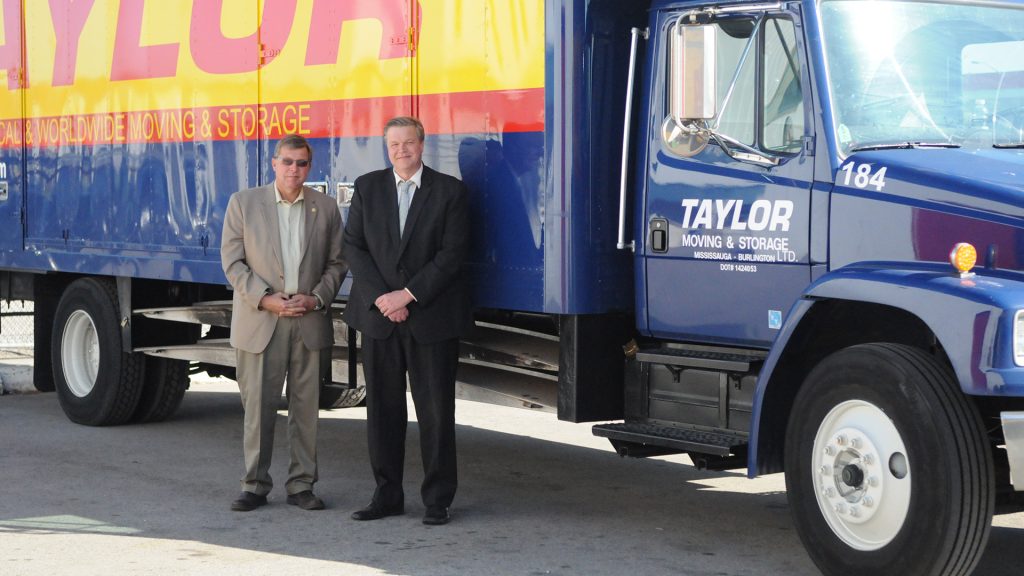 Rick and Russ Taylor standing next to a Taylor Moving truck