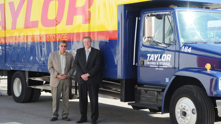 Rick and Russ Taylor standing next to a Taylor Moving truck