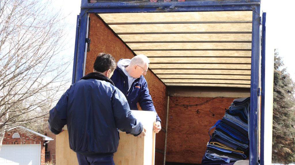 Two people moving a crate into a moving truck