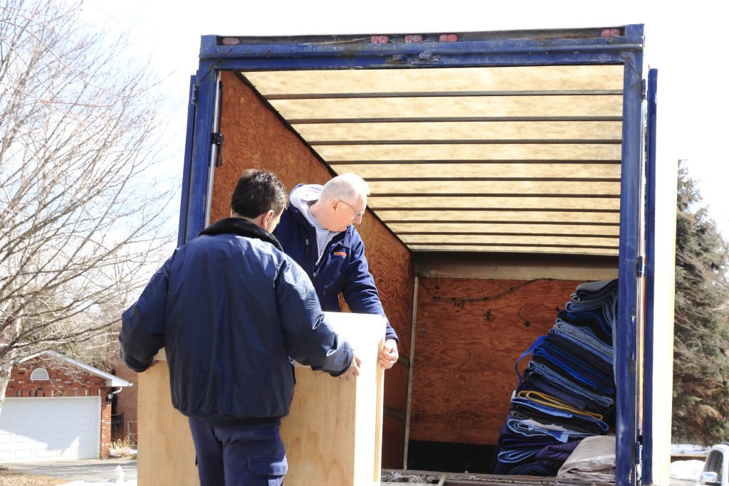 Two people moving a crate into a moving truck