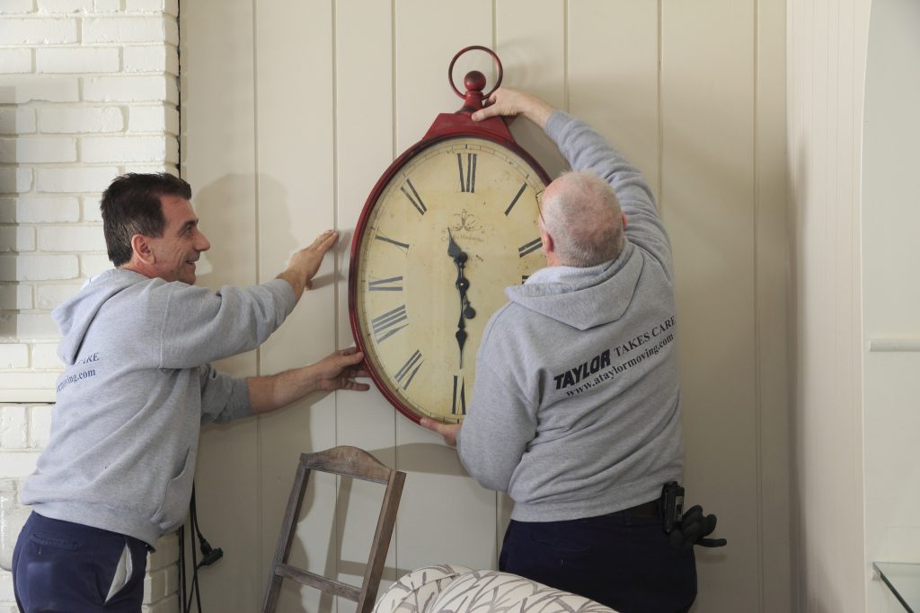 Two movers taking a big clock off a wall