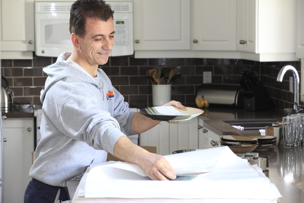 Man wrapping plate in paper
