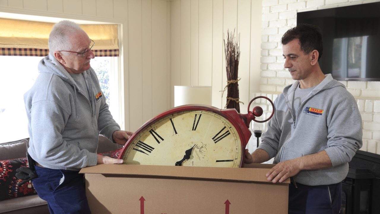 Two people packing a clock in a box