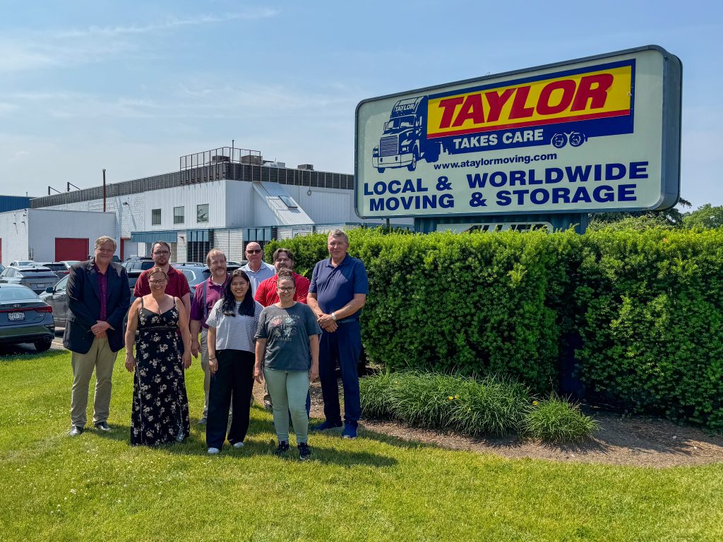 The Taylor team standing outside in front of a Taylor Moving sign