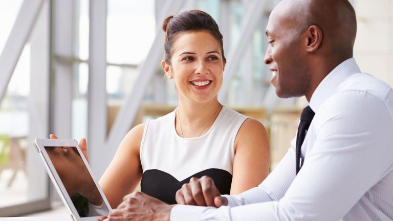 A man and women discussing in front of a laptop