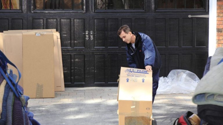 A person is moving boxes in front of a garage door.