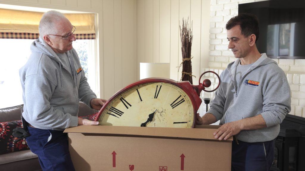 Two people packing a clock in a box