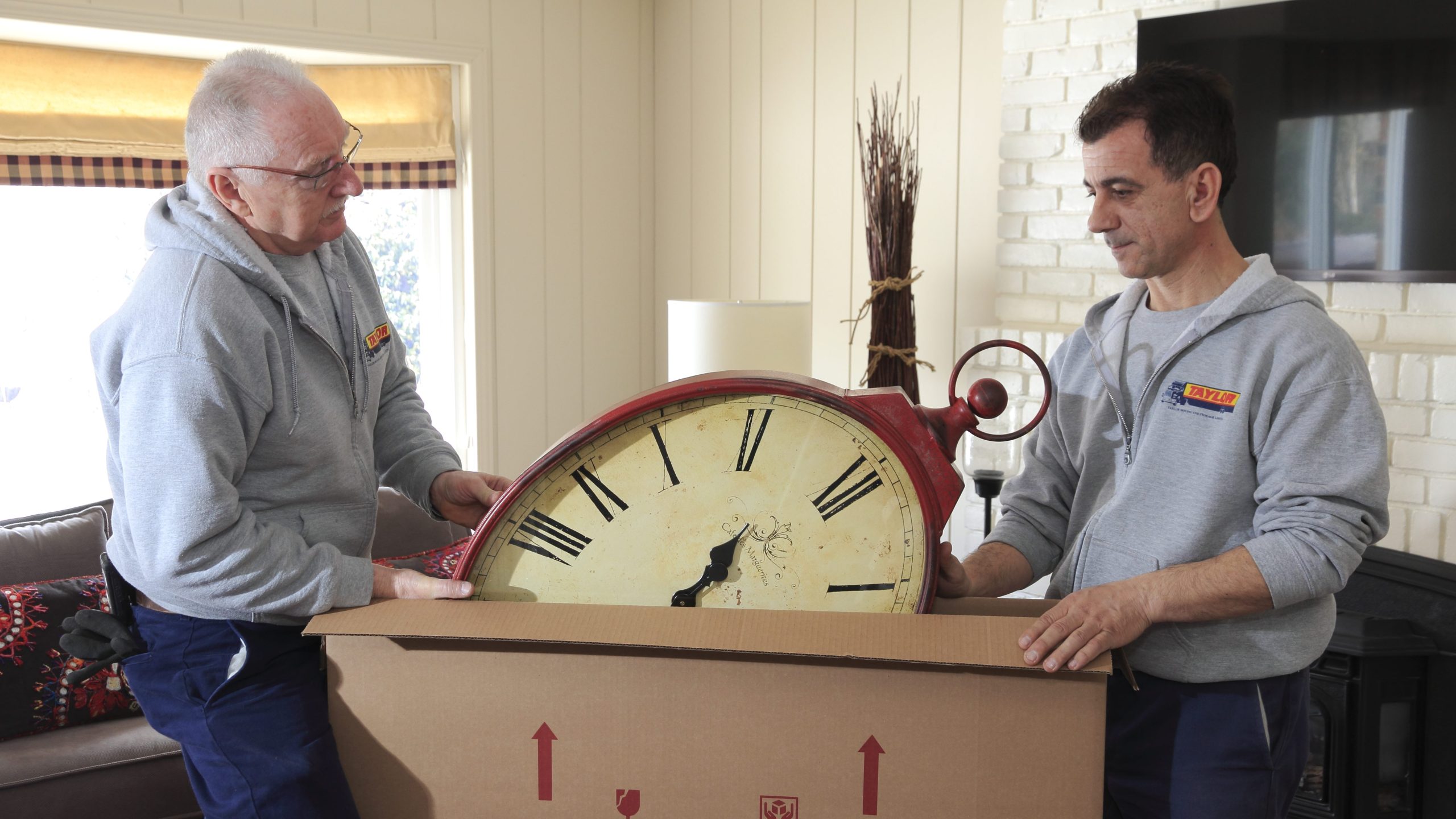 Two people packing a clock in a box